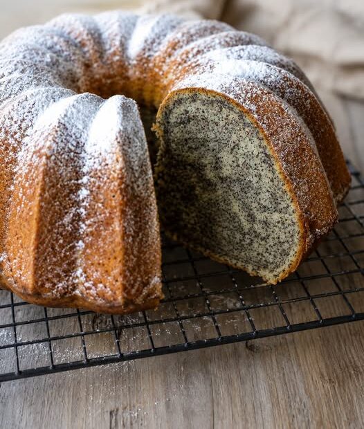 Saftiger Mohn-Gugelhupf mit feiner Vanillenote und Puderzucker auf einer Kuchenplatte